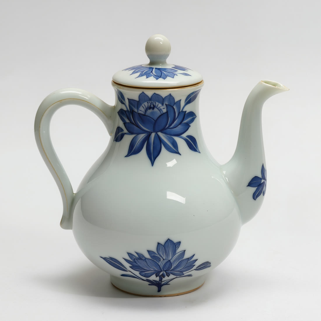 A porcelain teapot with blue floral patterns on a plain studio background.